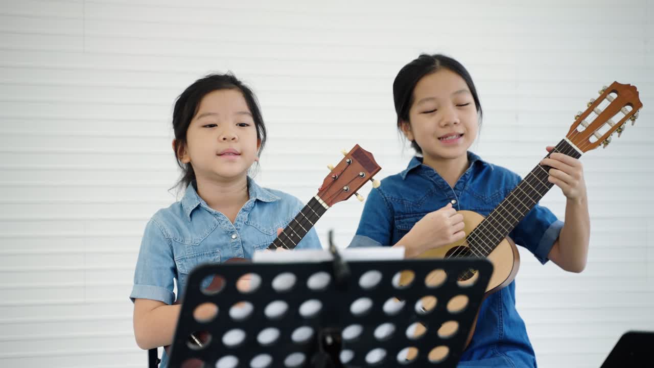 In a music school, a beautiful Asian teacher is teaching students to play music and sing, the concept of education, child development.