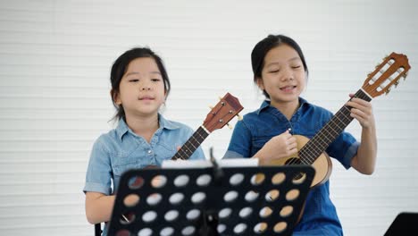 in a music school, a beautiful asian teacher is teaching students to play music and sing, the concept of education, child development.