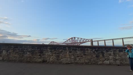 people and dogs walking by forth bridge