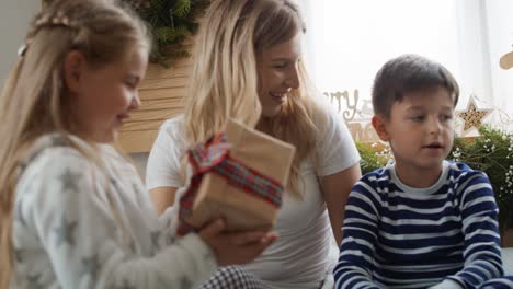 family sharing the christmas presents in bed