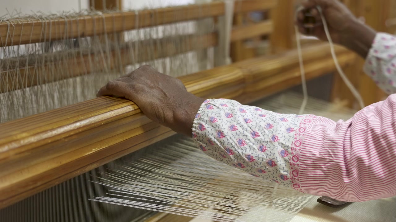 Hands operate traditional wooden weaving loom. Perfect for documentary or educational film.
