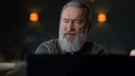 Senior man talking video call home. Senior businessman using laptop indoors.