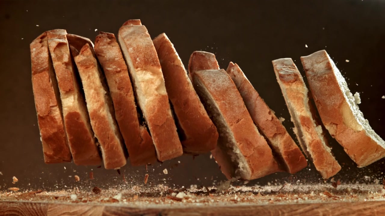 Fette di pane fresco che cadono al rallentatore su un tagliere di legno rustico
