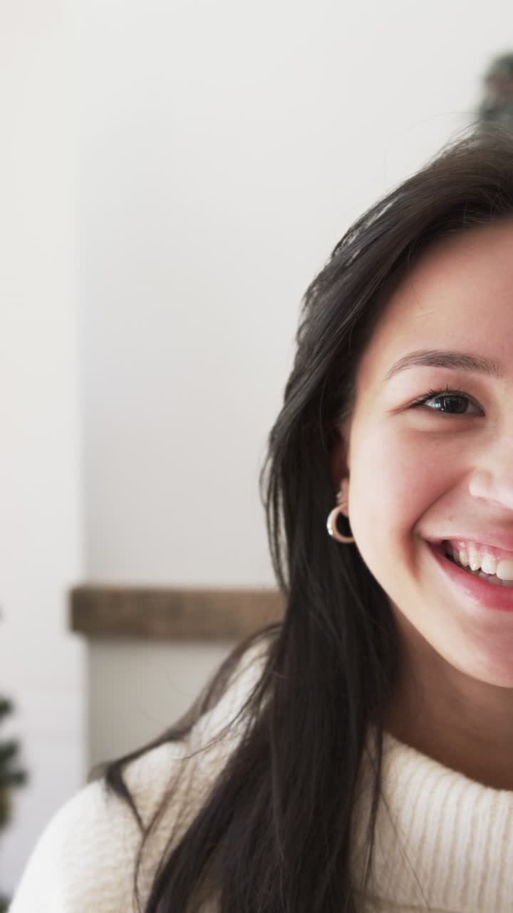 Vertical video portrait close up of happy biracial woman smiling at home at christmas, slow motion