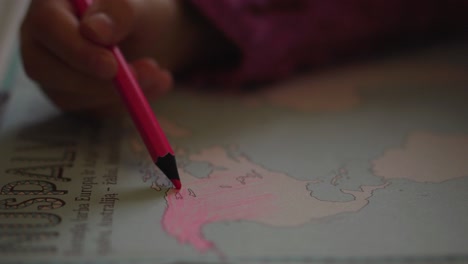 Una-Niña-Pequeña-Está-Coloreando-El-Continente-De-América-Del-Norte-Con-Un-Lápiz-Rosa-En-Un-Libro-Educativo-2-Del-Atlas-Mundial