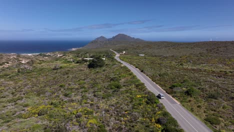 aerial drone shot of a van driving along beautiful coastal road in cape point national park in cape town