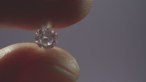 una persona hace rodar un diamante entre sus dedos