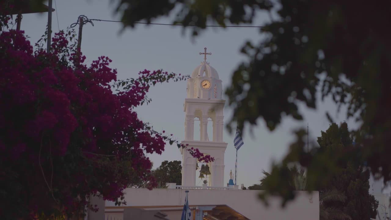 pintoresca vista de la bandera griega en mykonos, grecia junto a una iglesia ortodoxa griega y una cúpula azul en el fondo