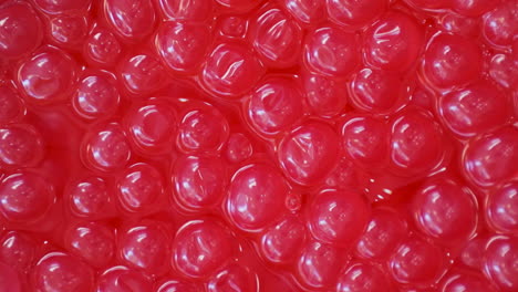 bobas de granada para té de burbujas hechas con agar agar y jugo de fruta en un recipiente