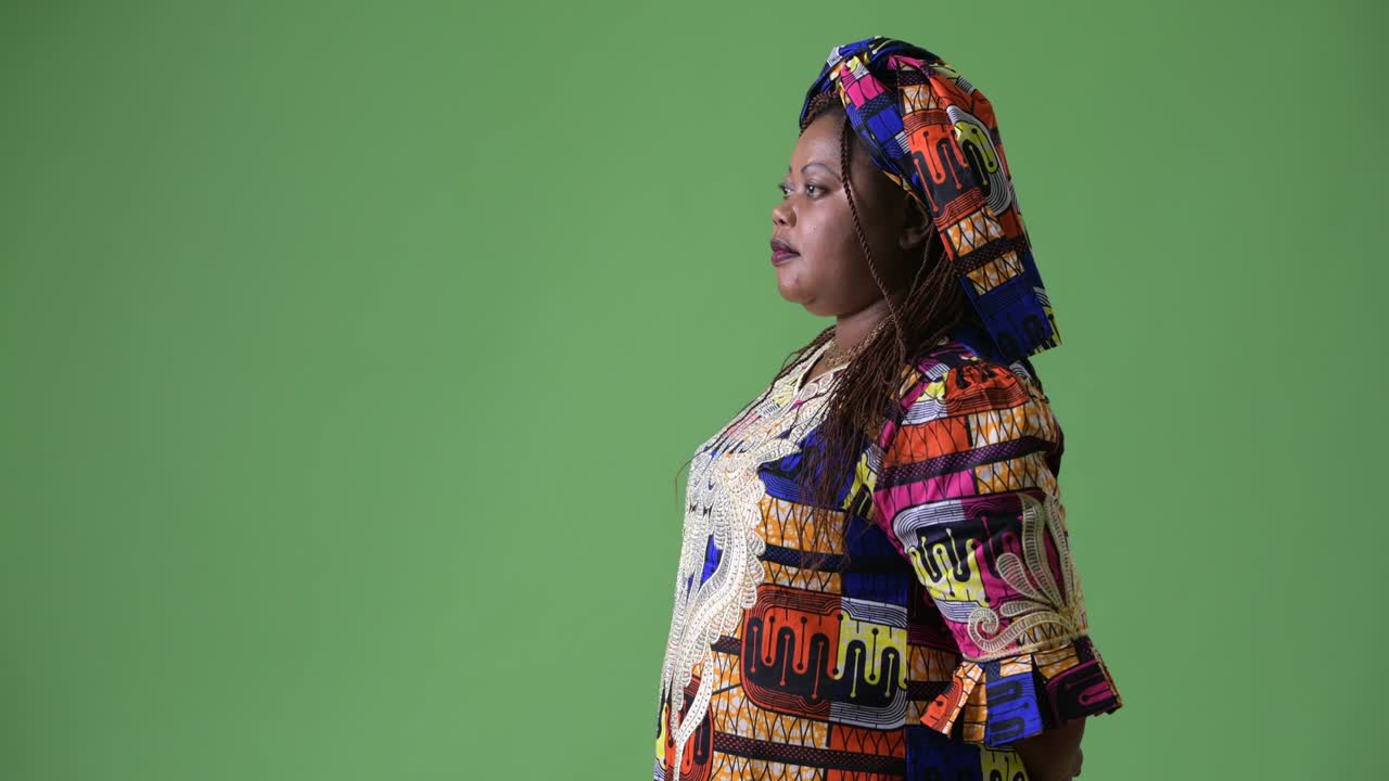 una hermosa mujer africana con sobrepeso que lleva ropa tradicional contra un fondo verde