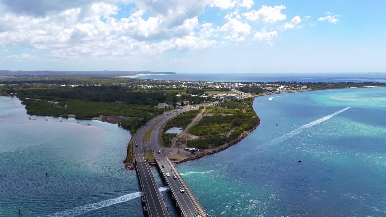 Wide aerial panorama of cars crossing Swansea bridge area with lake and coastal town in distance
