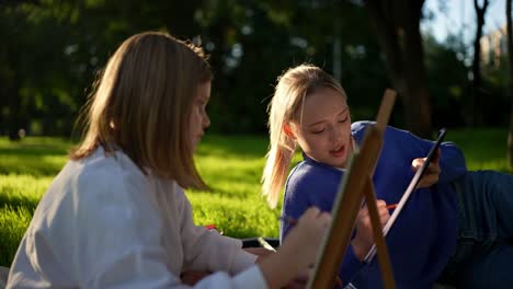 two girls painting outdoors in a park