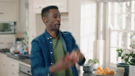 happy-african-american-man-dancing-in-kitchen-juggling-with-apples-having-fun-celebration-enjoying-weekend-at-home