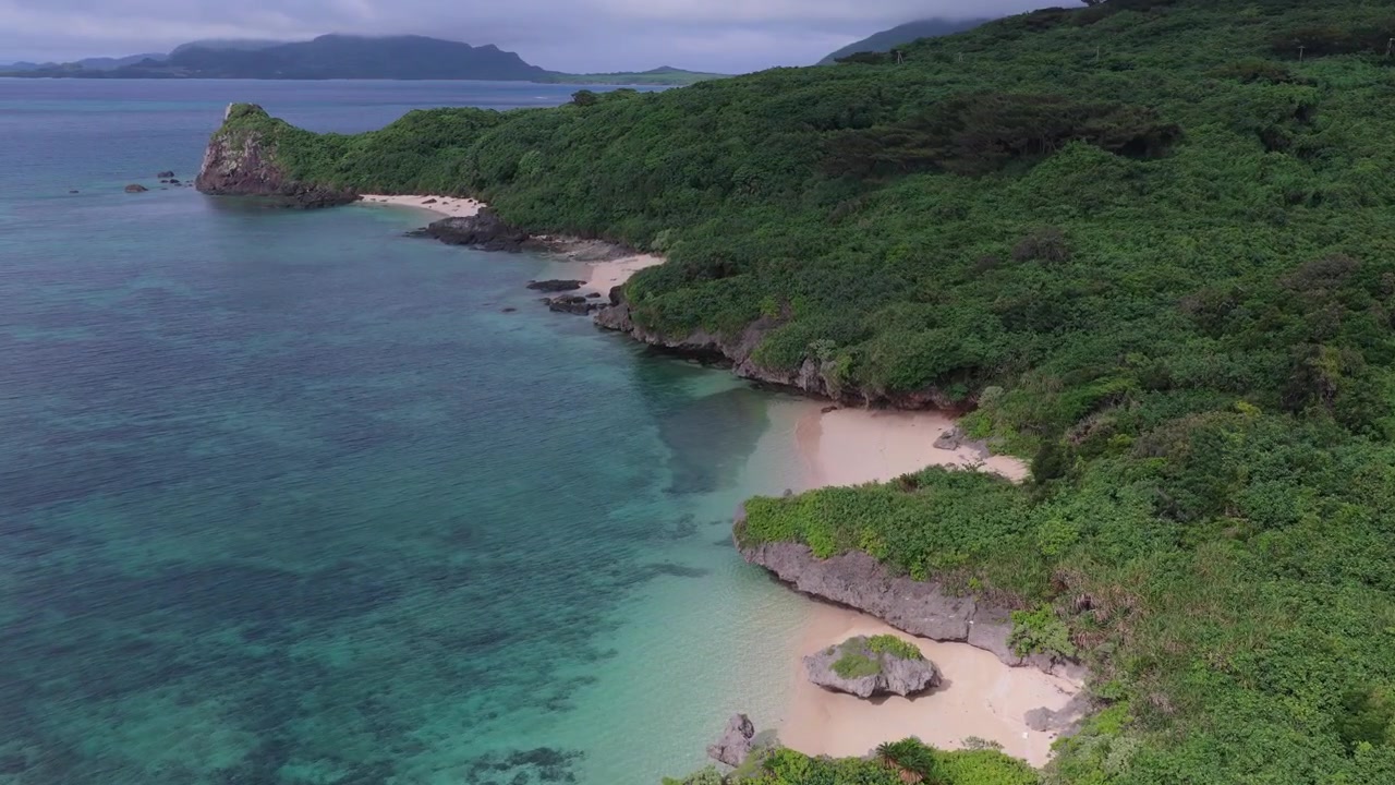 Japonya, Okinawa, Ishigaki Adası'ndaki Nosokoniaru Plajı ve Ibaruma Koyu'nun gözlerden uzak plajları, ormanlık kıyı şeridi ve turkuaz suları üzerinde ileri doğru kaydırılan yatay hava çekimi.