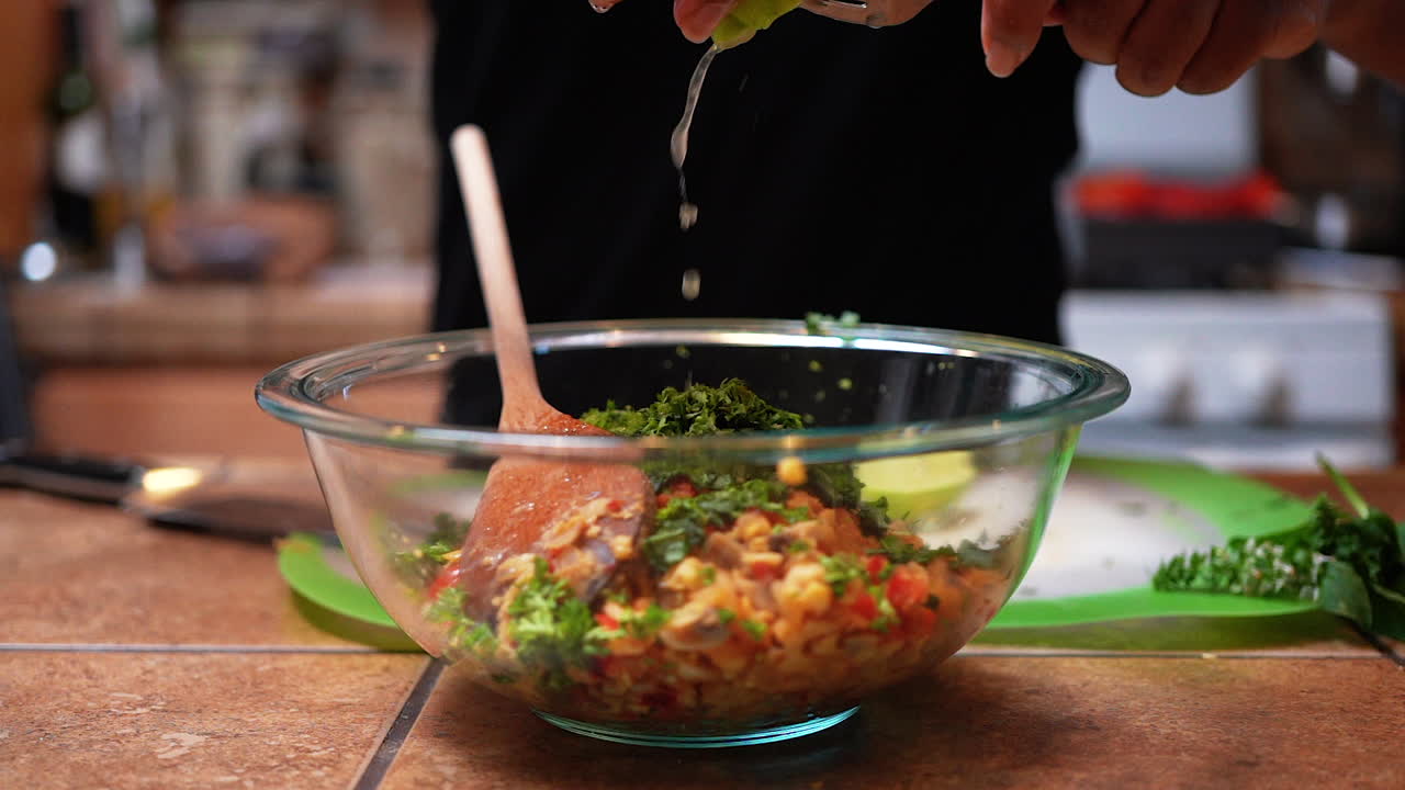 exprimir jugo de lima fresco en un tazón de ingredientes para hacer un delicioso relleno o ensalada - cámara lenta