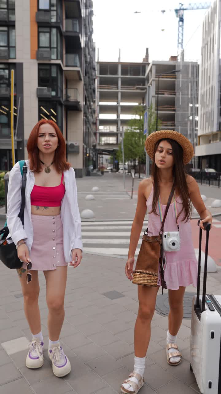 Due ragazze che camminano in città con i bagagli