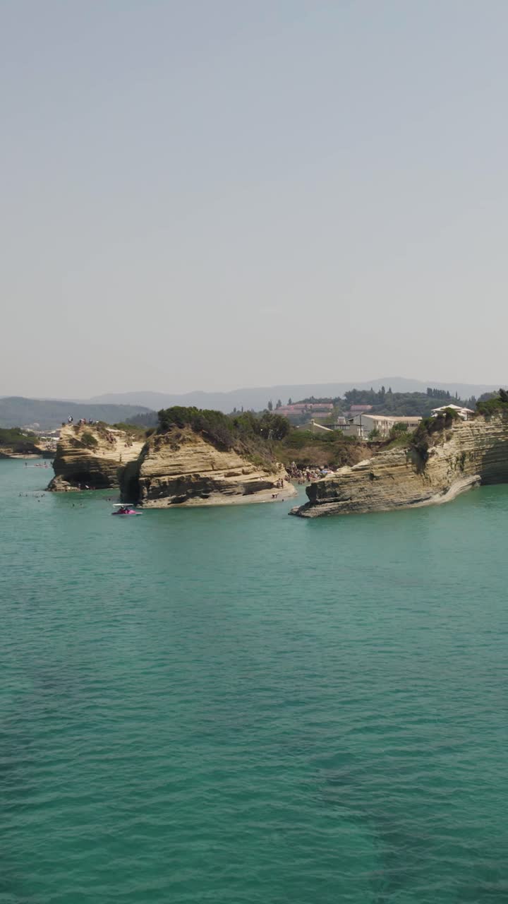 Aerial view of the iconic Canal D’Amour in Sidari, Corfu, on a sunny summer day, showing its turquoise waters and unique sandstone formations