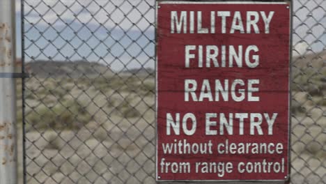 high quality 3d cgi render of a chainlink fence at a high security installation in a desert scene, with a military firing range no entry sign