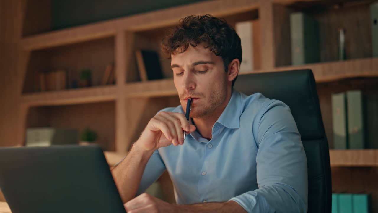 Busy freelancer looking laptop pondering business issue late evening close up.