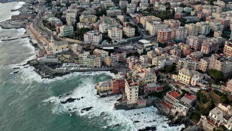 Aerial-arcing-view-of-Boccadasse-beach-in-Genoa-surrounded-by-buildings-on-shore