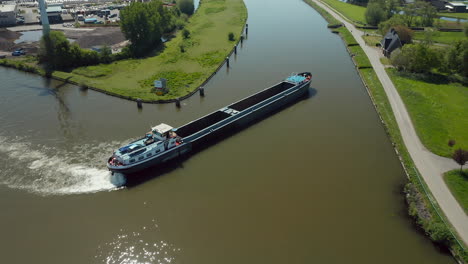 long wooden barge sailing through the narrow canal in zuidelijk halfrond province, south holland, netherlands