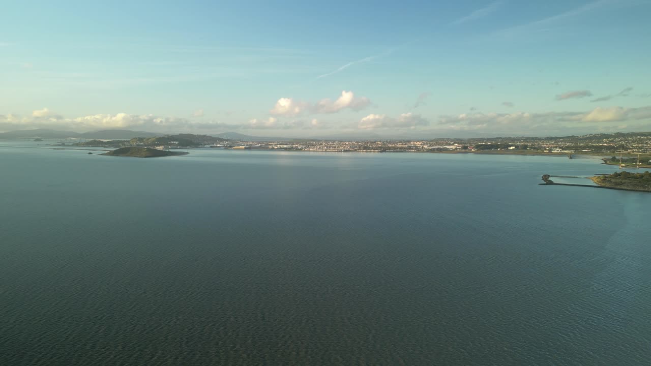 광활한 세자르 차베스 공원, 조용한 샌프란시스코 만 물, 버클리 마리나, 그리고 배경의 굴곡 언덕을 포착하는 항공 사진.