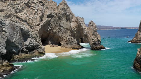 toma de drones de el arco y playa del amor revelando lentamente barcos en el océano en cabo san lucas méxico