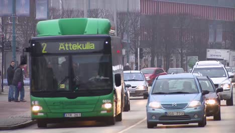 busy city street with cars and a green bus during a cloudy day in sweden