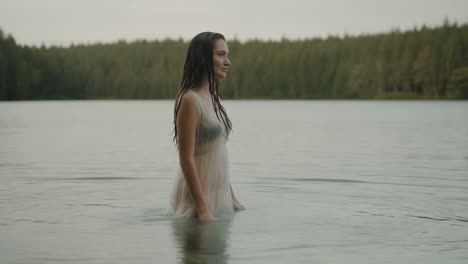 a woman stands in a calm lake surrounded by nature