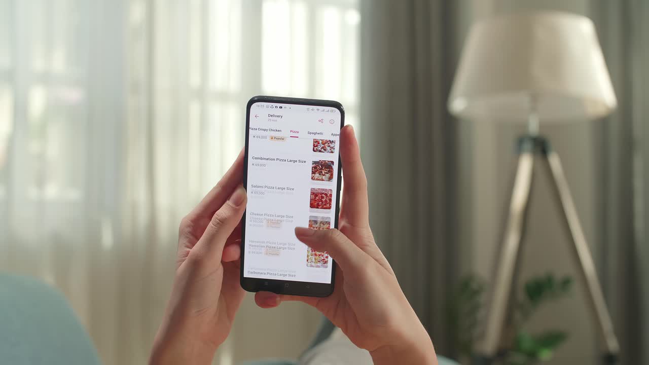 Close Up Of Hand Woman At Home Lying On Couch In Living Room Using Smartphone Buys In Internet Shop. Female Hand Orders Food In An Online Store Using A Smartphone