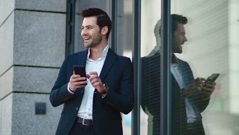 Closeup-man-standing-in-black-suit-at-street.-Businessman-using-smartphone