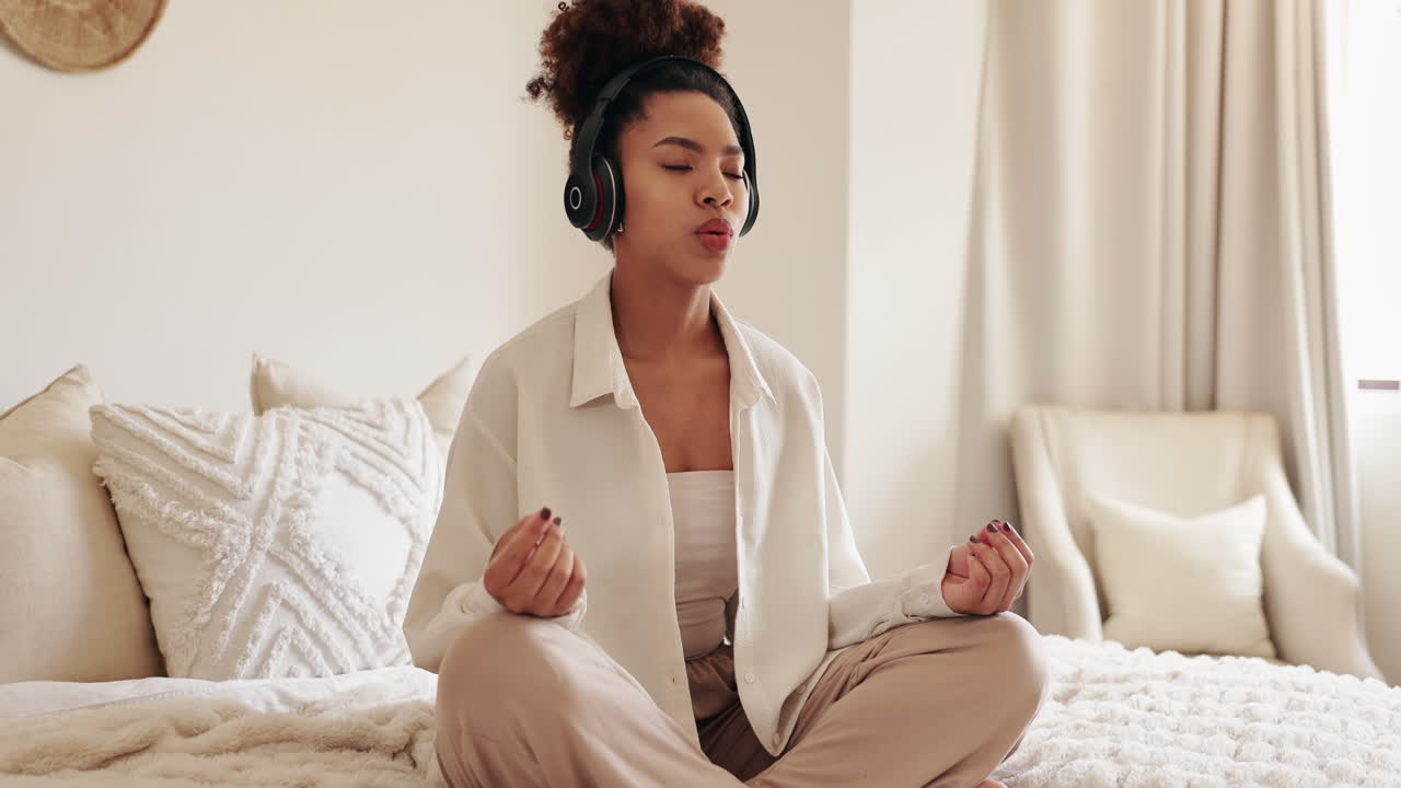 mujer joven meditando con auriculares en el dormitorio