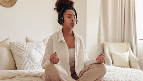 young woman meditating with headphones in bedroom