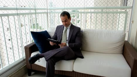 man in a suit and tie working, looking at his tablet and celebrating good news.