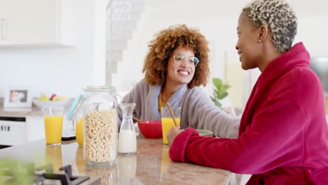 feliz pareja de lesbianas diversas hablando y desayunando en la cocina en cámara lenta