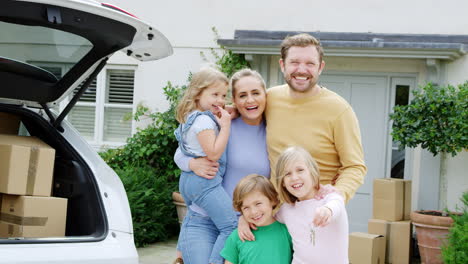 Retrato-De-Familia-Fuera-De-Casa-Nueva-Con-Llaves-En-El-Día-De-La-Mudanza-Descargando-Cajas-Del-Coche