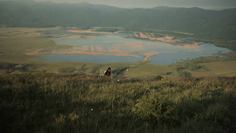 man hiking up a hill of mountain slivnica, camera boom up to revel more of the valley with seasonal lakes of cerknica