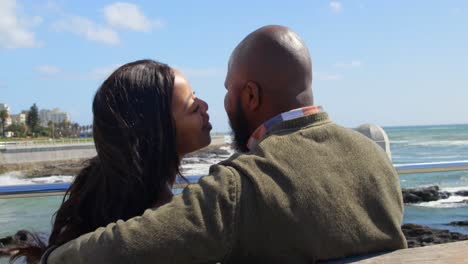 Couple-kissing-on-bench-near-railing-on-a-sunny-day-4k