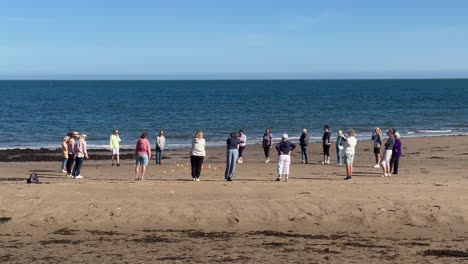 women engage in a spirited match of beach bowls, enjoying the sun and sea breeze during the outdoor activity.