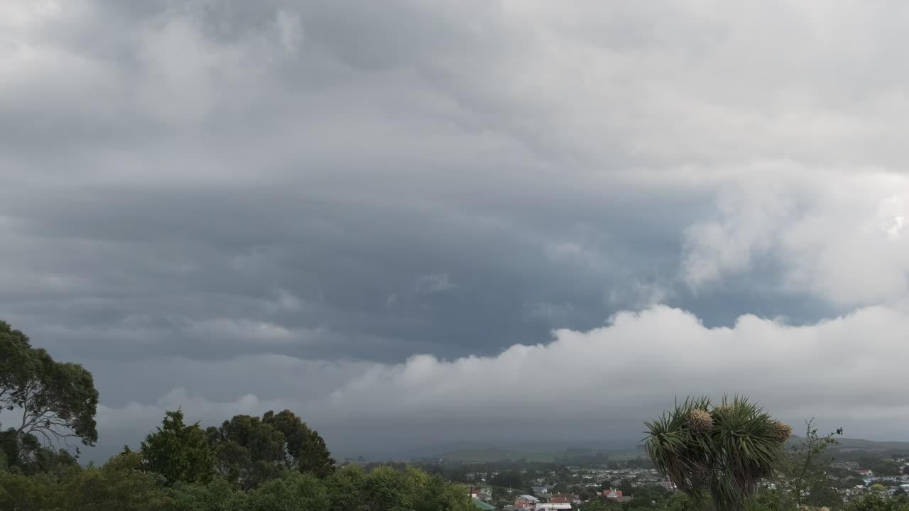 A storm front moves towards a charming town nestled in New Zealand's rolling hills