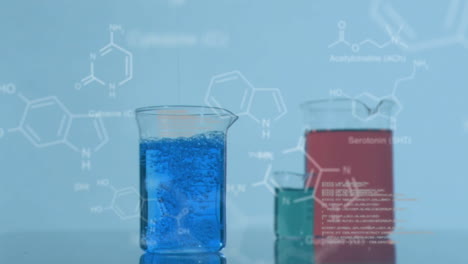vasos de laboratorio con datos y fórmula estructural de compuestos químicos en primer plano