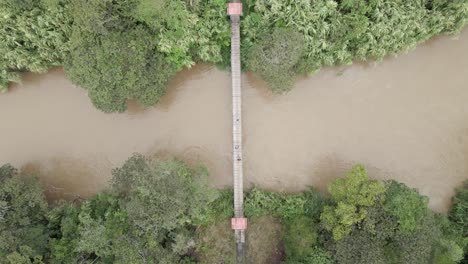 Antena:-La-Gente-Camina-A-Través-Del-Estrecho-Río-De-La-Jungla-En-El-Puente-Colgante