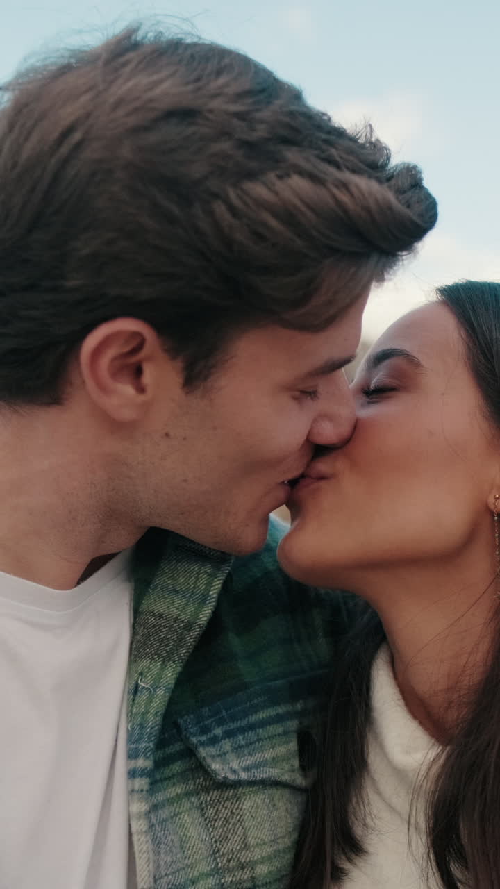 Primo piano di due giovani partner felici, un uomo e una donna, che si abbracciano e si baciano mentre sono in piedi
