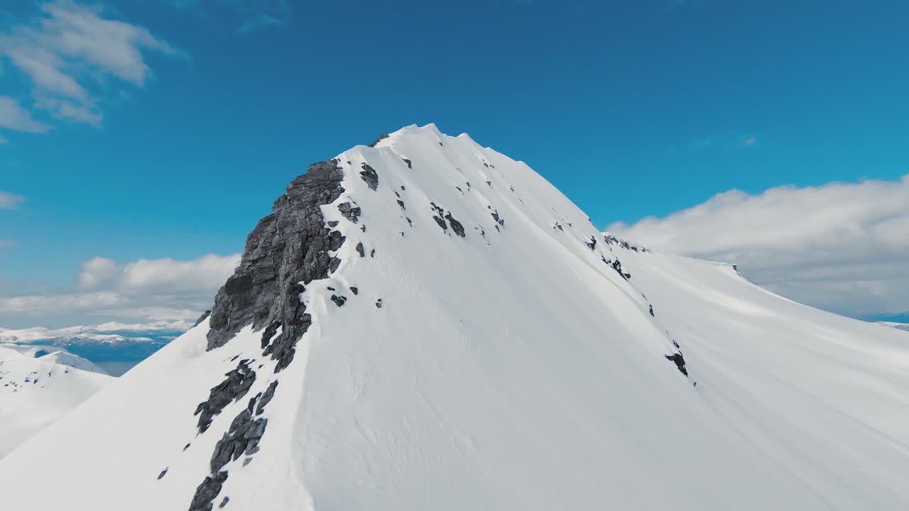 fpv rápido volando hacia la cima de una montaña cubierta de nieve en noruega
