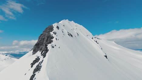 Fpv-Rápido-Volando-Hacia-La-Cima-De-Una-Montaña-Cubierta-De-Nieve-En-Noruega