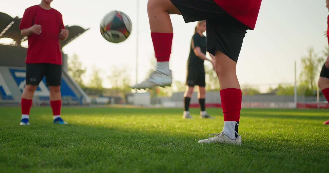 Calciatrici che palleggiano il pallone e si esercitano nella tecnica di base su un campo verde