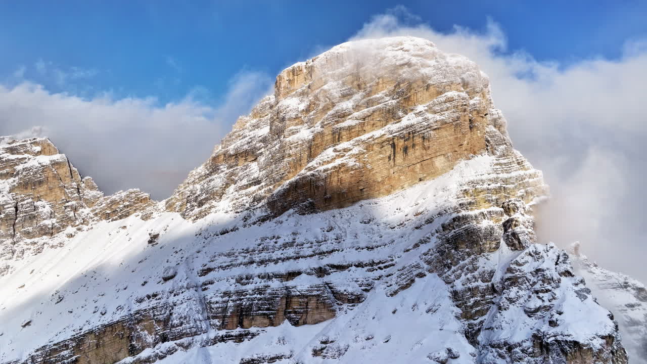 Aerial drone view of snow on the Sassongher mountain in the Dolomites, Italy with the blue sky on the background
