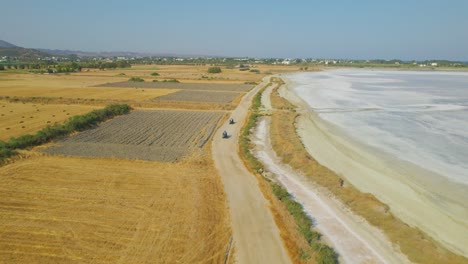 Vehículos-Todo-Terreno-Conduciendo-Al-Lado-Del-Lago-Salado-En-El-Campo-Griego,-Vista-Aérea