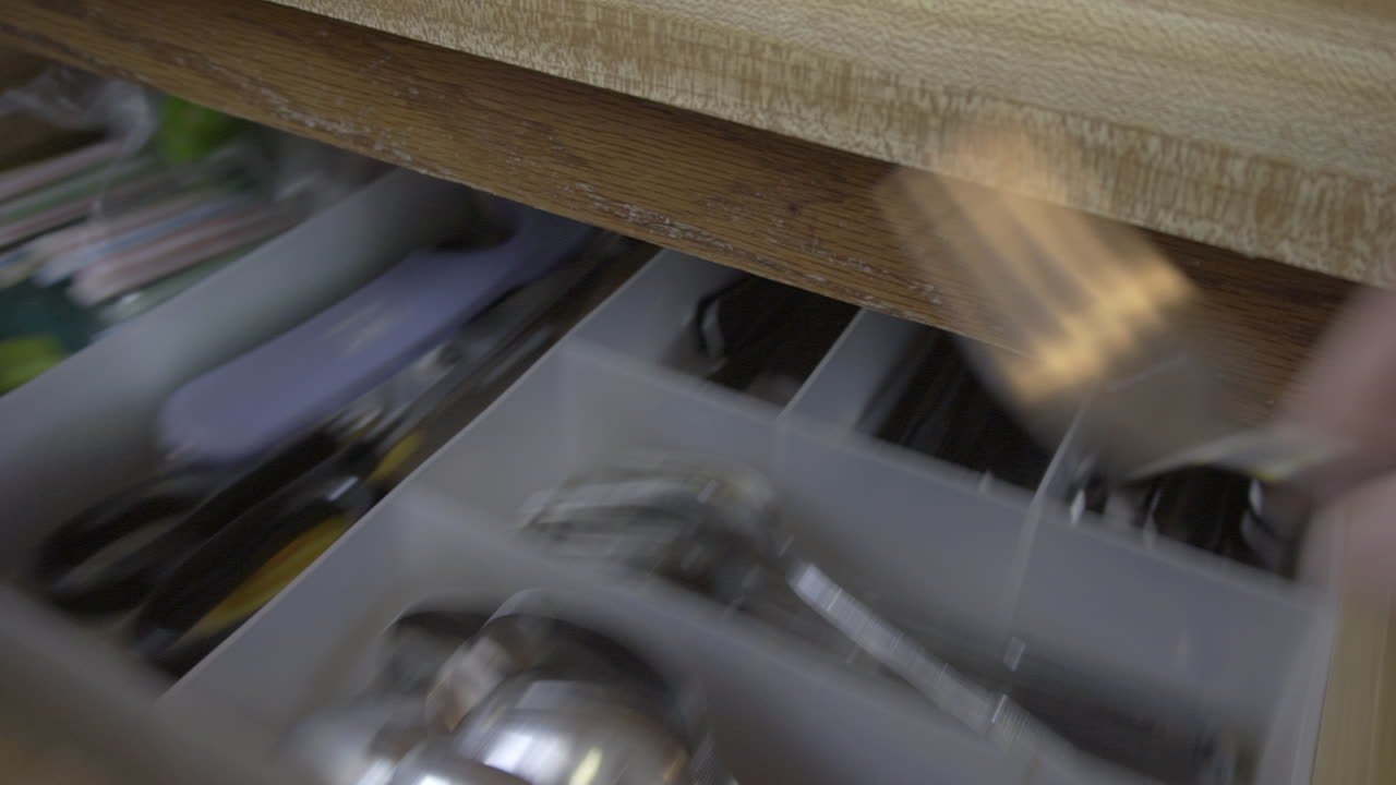 Clip di una mano che afferra una forchetta in un cassetto della cucina