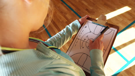 female coach making basketball strategy on a clipboard